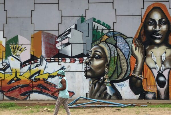 A woman walking by a wall mural in Senegal